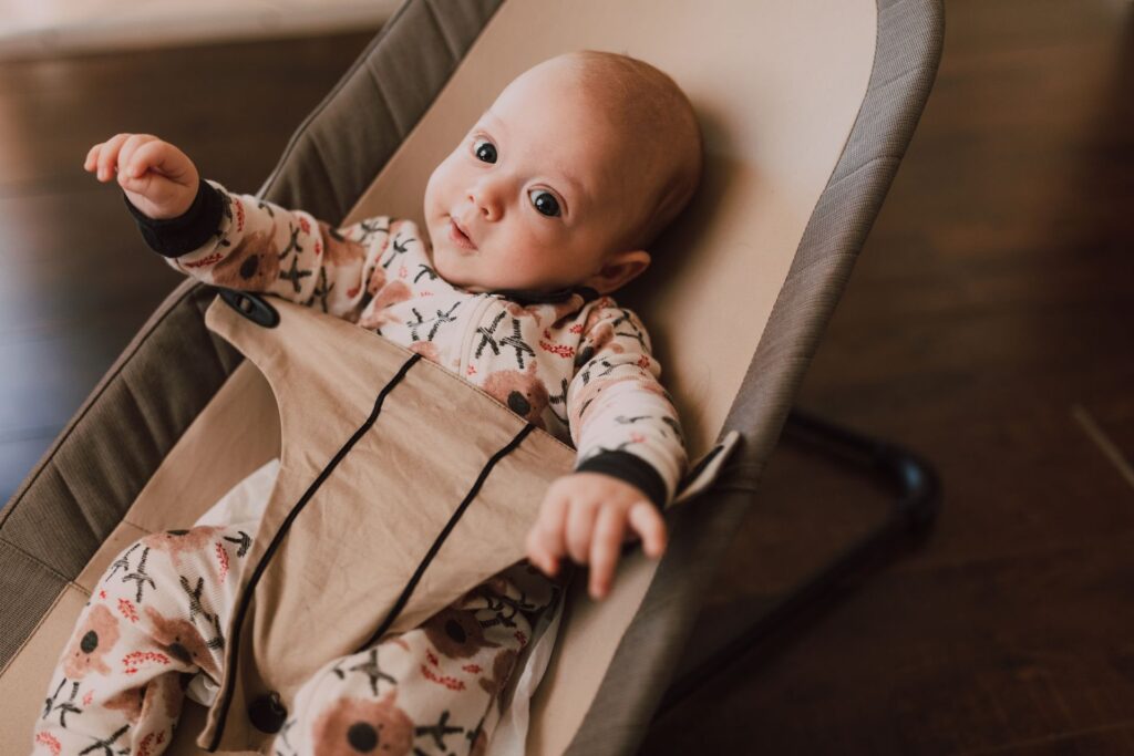 Baby liegt aufmerksam in einer Babywippe