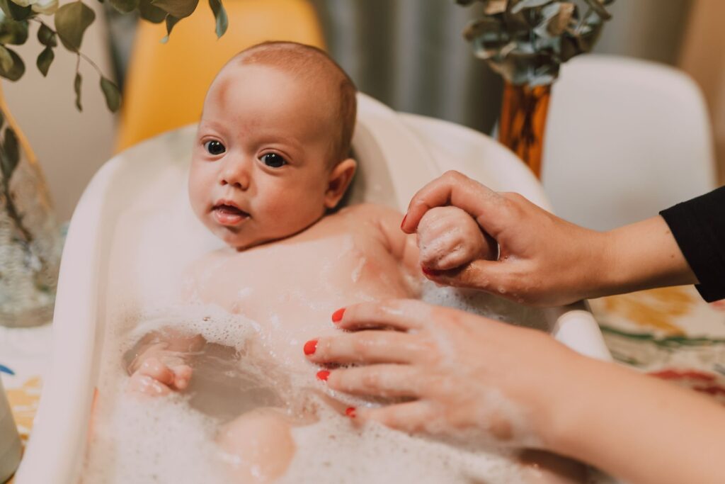 Baby wird von seiner Mama in einer kleinen Babybadewanne gebadet